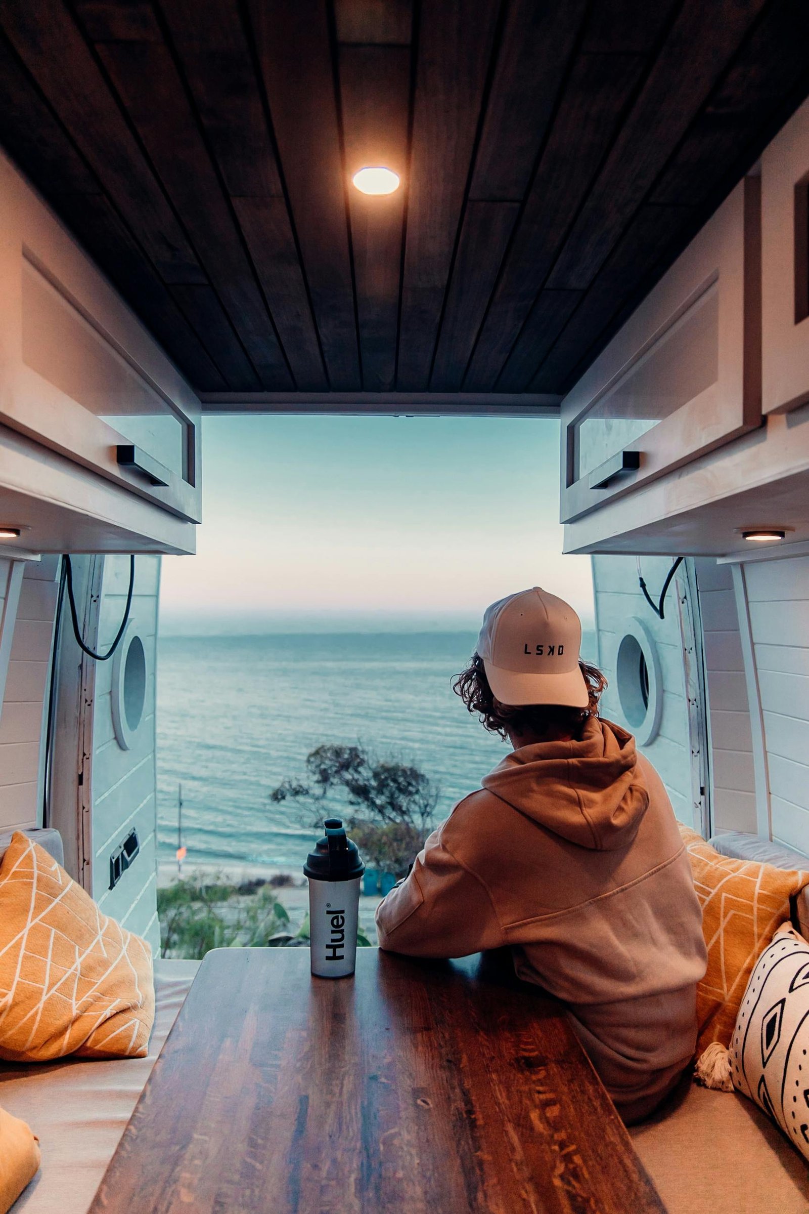A man sits in a camper van, enjoying a scenic ocean view in Malibu, California.